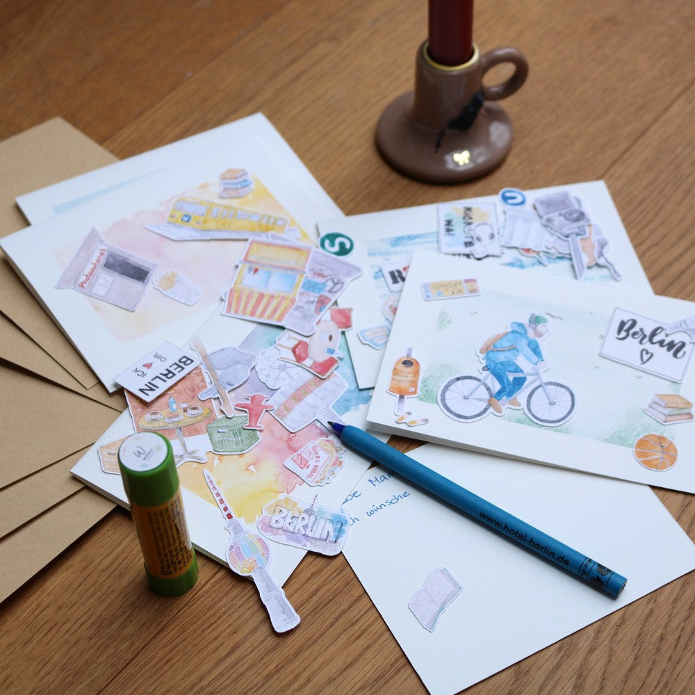 Kreativ Set Berlin - Karten mit aufgelegten Motiven wie Fahrradfahrer, Mülleimer mit Klebestift und beschriebener Karte mit Stift