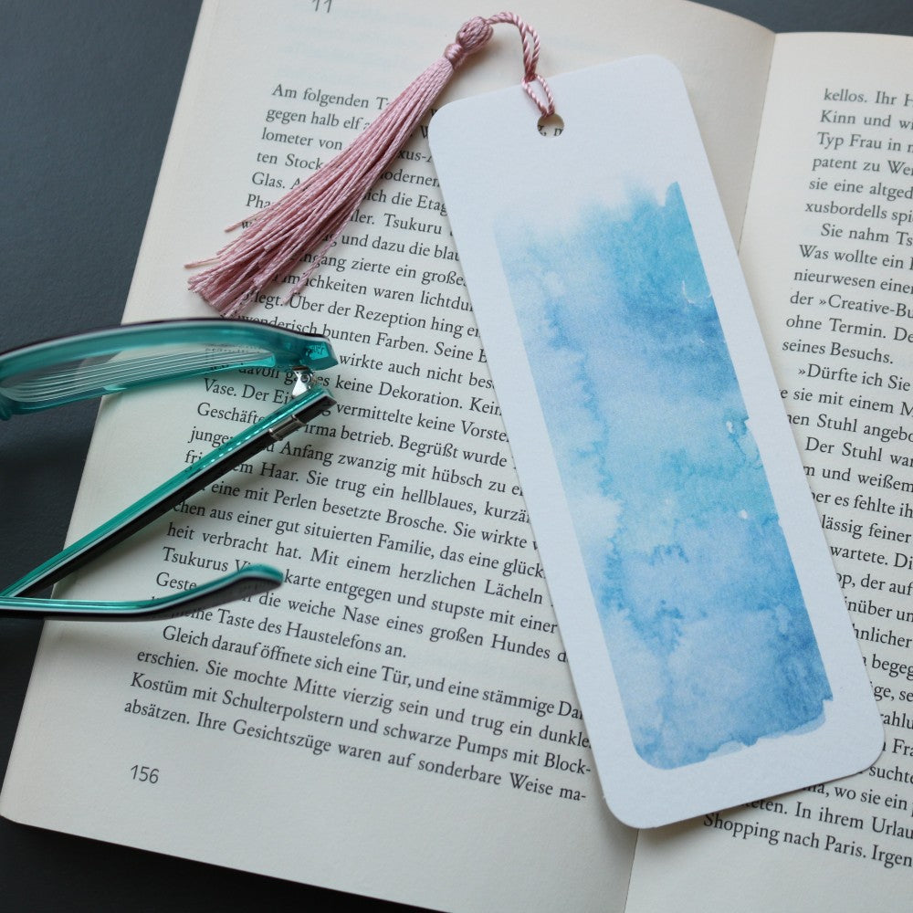 Lesezeichen-Set Im Meer: Blaues Aquarell-Lesezeichen mit Meeresstruktur und rosa Quaste als stimmungsvolles Accessoire beim Lesen.