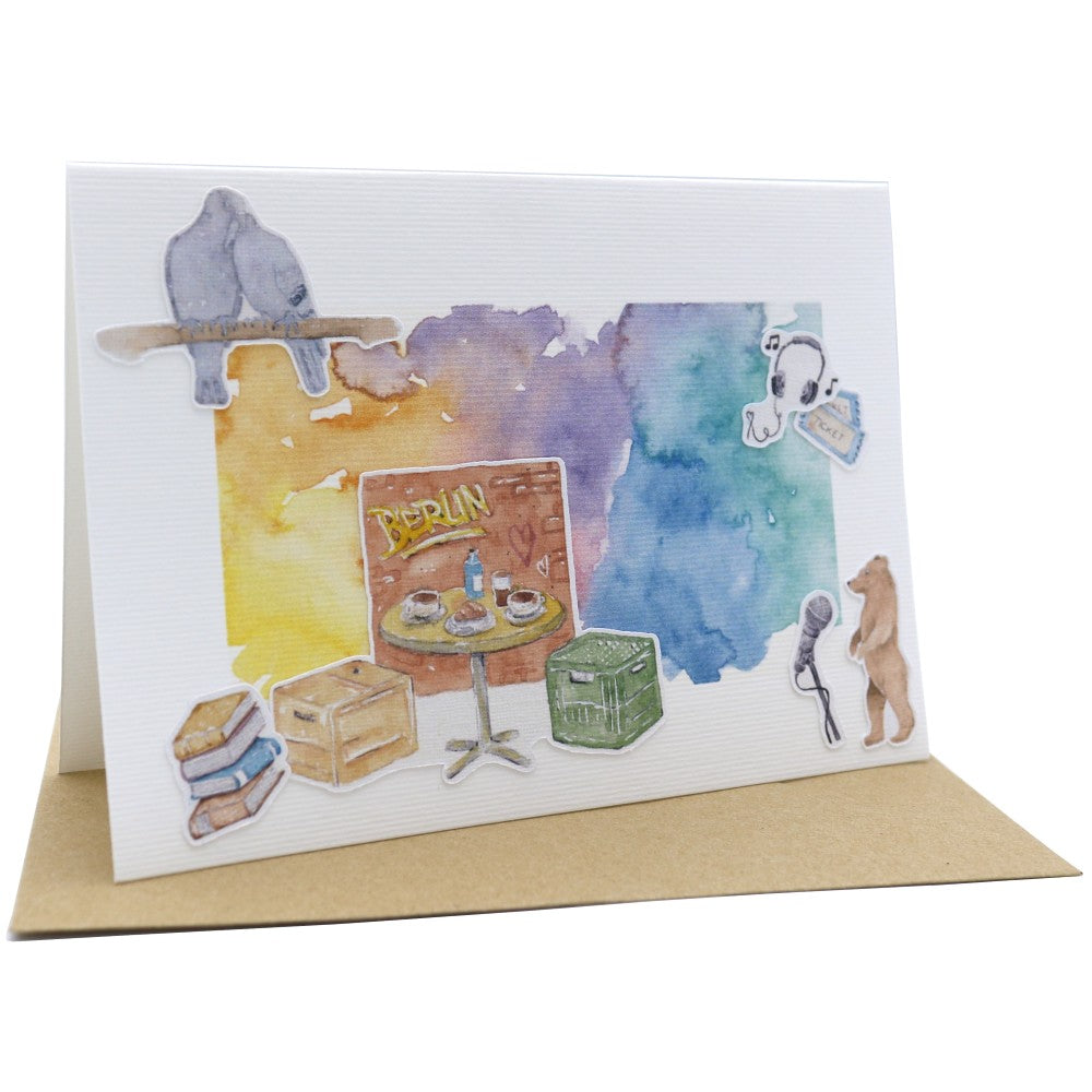 Berlin Klappkarte A6 mit Aquarellillustrationen eines Cafétischs, Berliner Alltagsobjekten und buntem Farbverlauf, mit Umschlag.