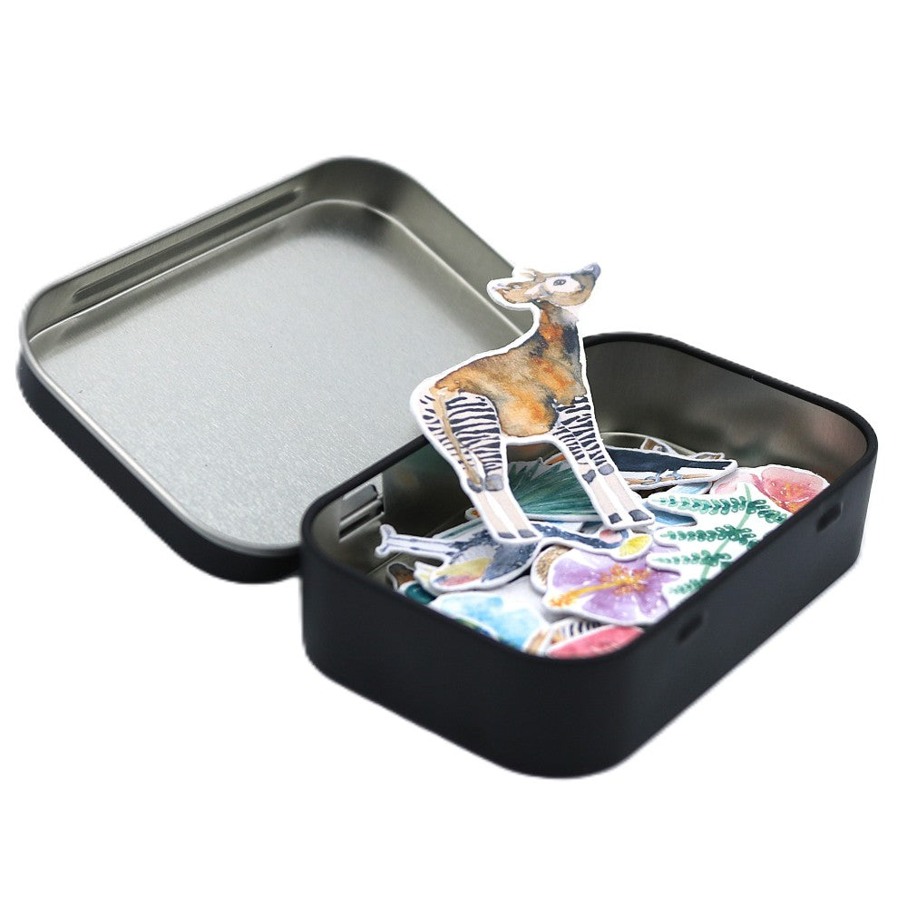 Stickerbox Tropenwelt Classic geöffnet – schwarze Metallbox mit handillustrierten Tropen-Stickern und Okapi-Motiv.