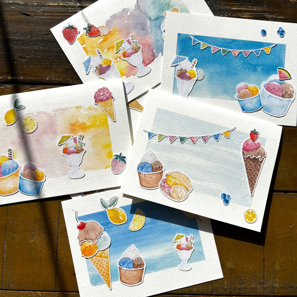 Karten mit Motiven zum Thema Eis, Eiswaffeln, Becher und bunte Girlanden, liegend auf einem Tisch