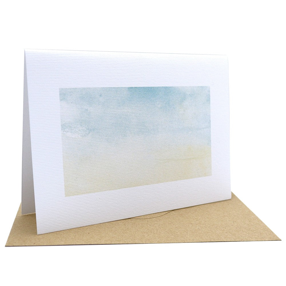 Klappkarte „Waldbewohner“ mit sanftem Aquarellverlauf in zarten Blau- und Beigetönen, inspiriert von Himmel und Erde; gedruckt auf hochwertigem strukturierten Aquarellpapier, inklusive braunem Kraftpapier-Umschlag, aufgestellt dargestellt.