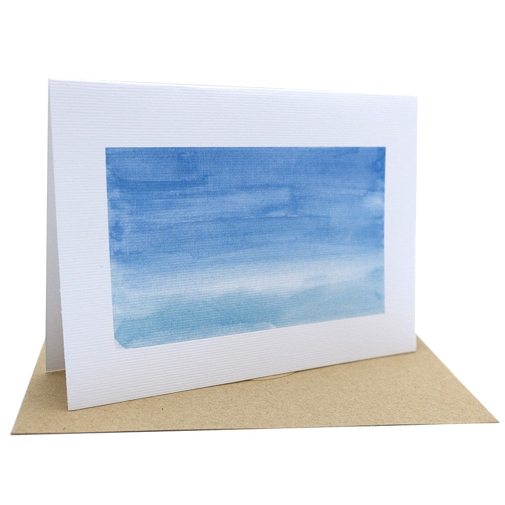Klappkarte Im Meer mit ruhigem Aquarellverlauf in Blautönen, der an das sanfte Spiel von Himmel und Wasser erinnert; auf strukturiertem Aquarellpapier, dazu ein naturfarbener Kraftpapierumschlag.