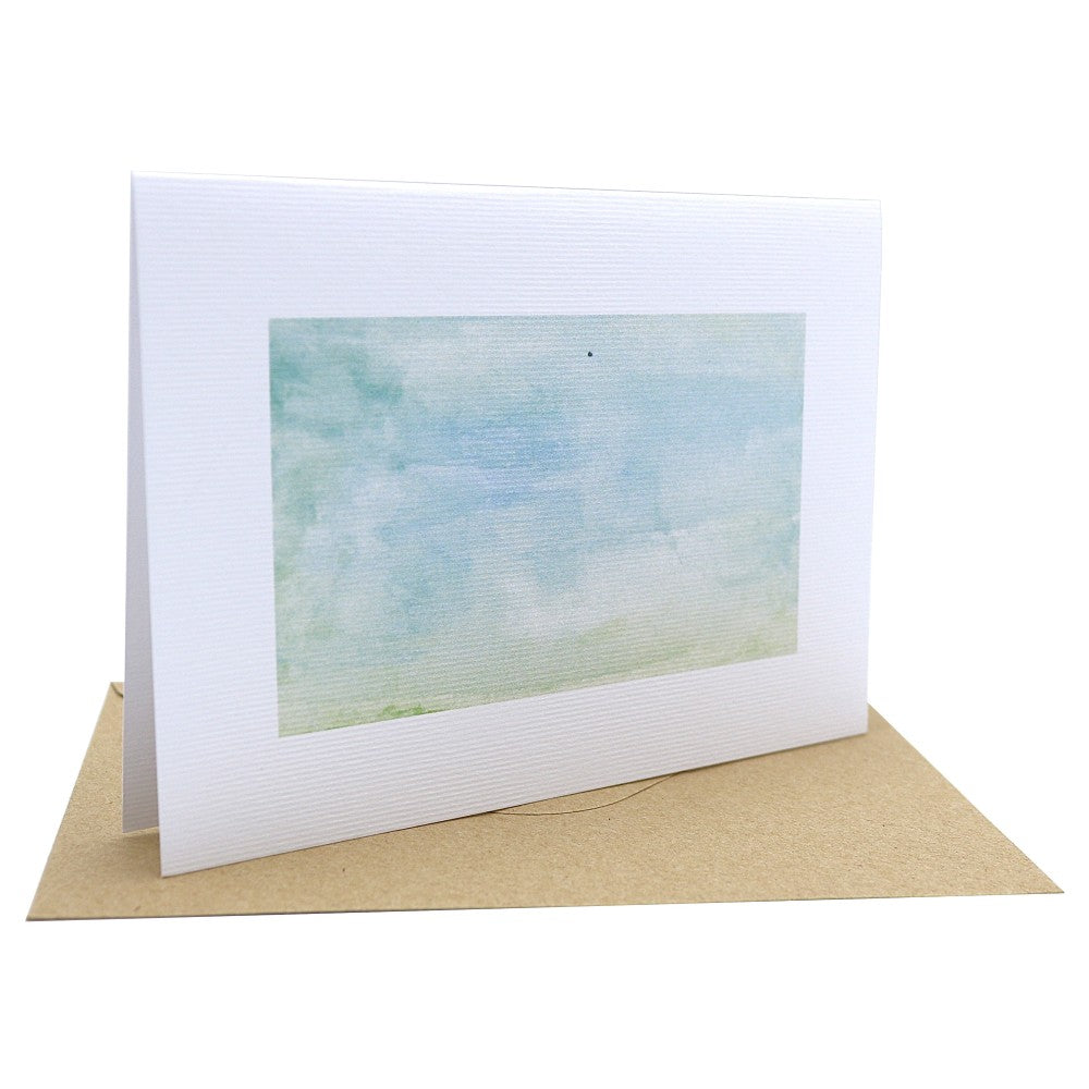 Klappkarte „Waldbewohner“ mit einem sanften Aquarell in Grün- und Blautönen – erinnert an nebliges Morgenlicht über einer Waldlichtung; gedruckt auf strukturiertem Aquarellpapier, ergänzt durch einen braunen Kraftpapier-Umschlag; aufgestellt dargestellt.