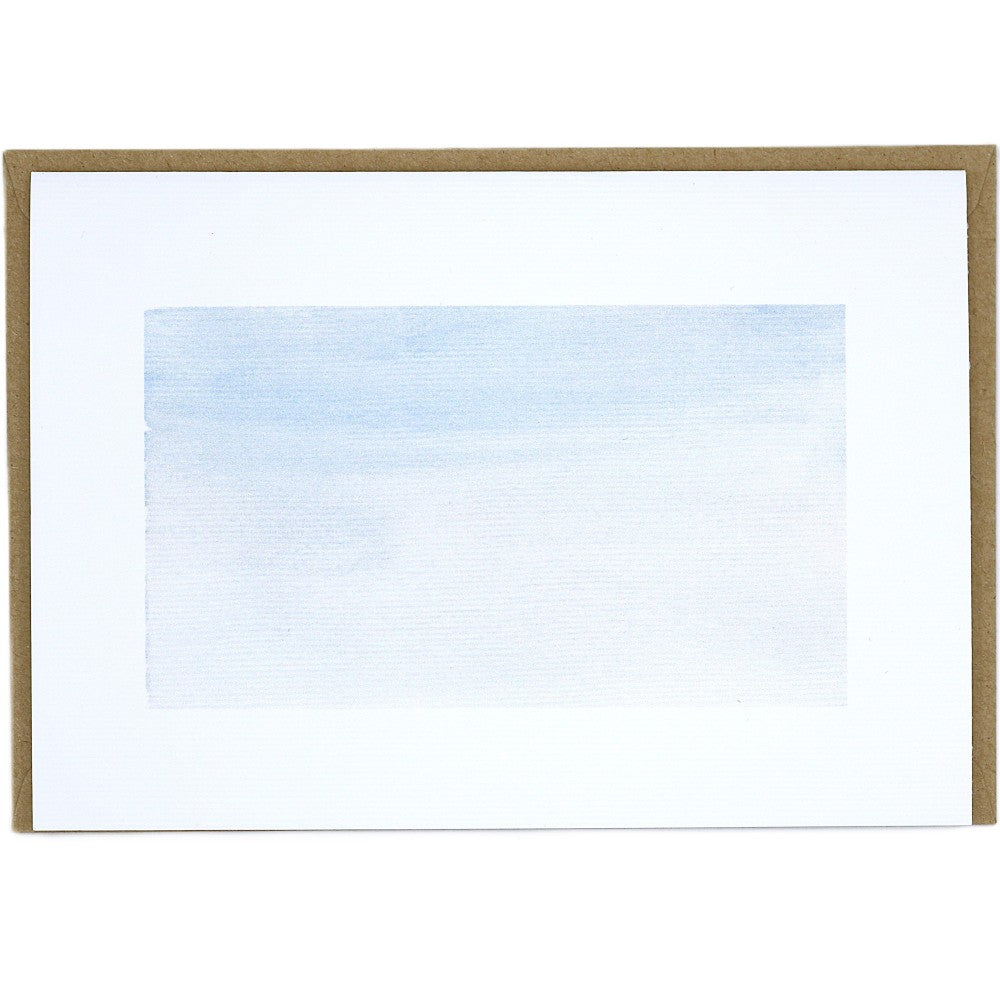Postkarte mit zartem winterlichem Aquarellhintergrund in hellen Blau- und Grautönen auf strukturiertem Aquarellpapier. Dahinter liegt ein passender Kraftpapier-Umschlag. Der Hintergrund ist ein Teil des Weihnachtskarten-Sets und zeigt eine sanfte, frostige Farbfläche ohne Motive.