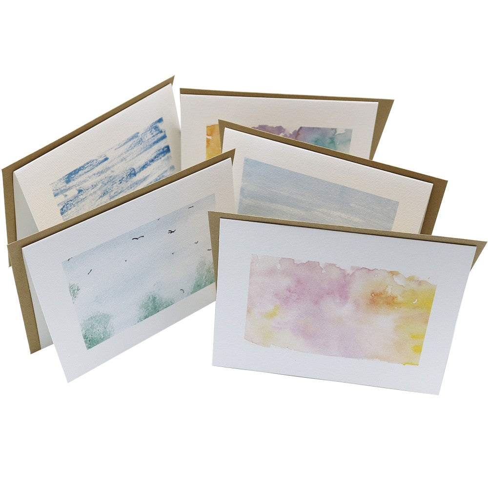 Geöffnete Klappkarten mit unterschiedlichen Aquarell-Hintergründen aus dem Berlin Kreativ Set, jeweils mit Kraftpapier-Umschlag