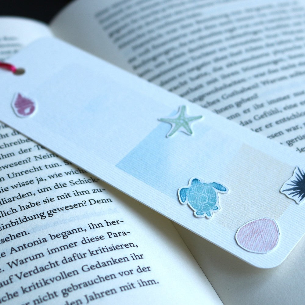 Lesezeichen Im Meer: Aquarell-Lesezeichen in Pastellblau mit Meeresschildkröte, Seestern und Muschelmotive, mit farbiger Quaste