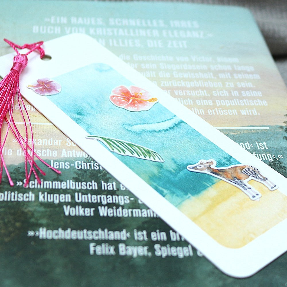Aquarell-Lesezeichen Tropenwelt mit pinker Quaste und handillustrierten Stickern: Blume, Blatt und Okapi, dekoriert auf einem Buch