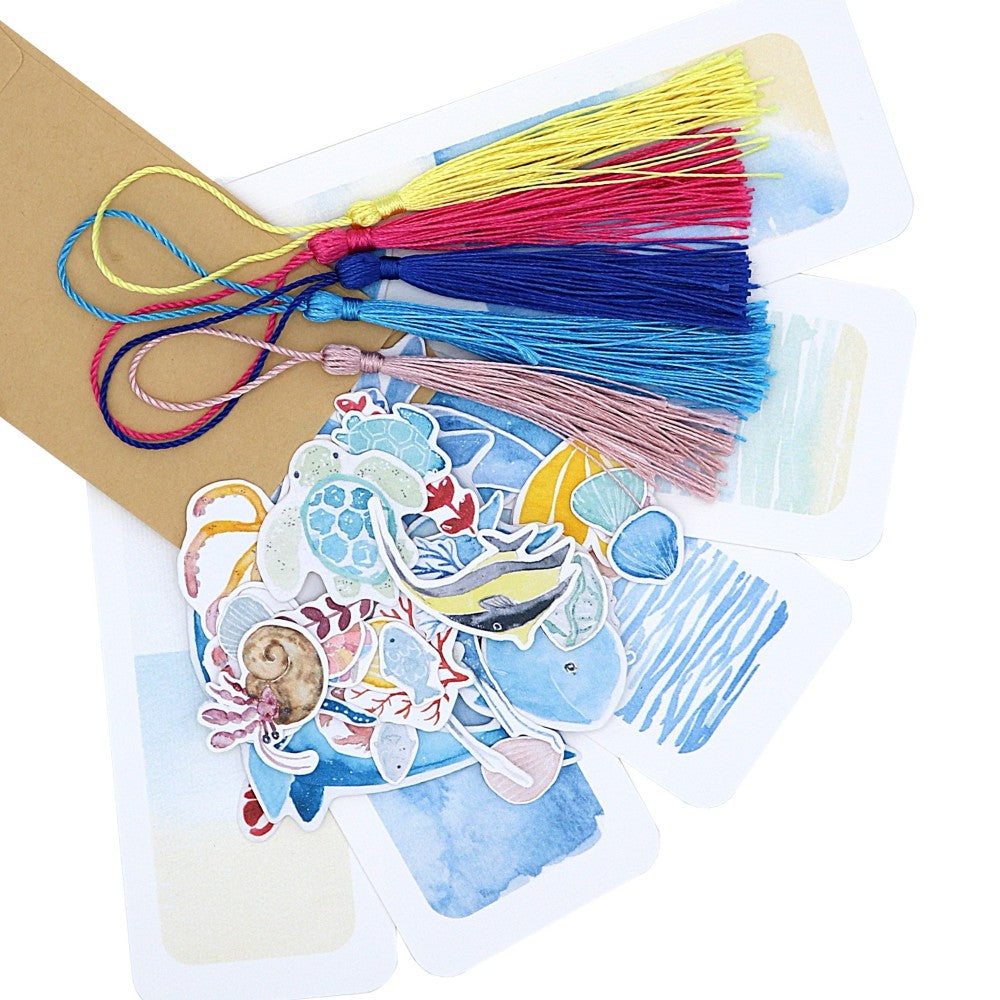 Kreativset Meer: Fünf Lesezeichen mit maritimen Aquarell-Hintergründen, dazu bunte Quasten und Meermotive wie Fische, Wale und Muscheln zum Selbstgestalten. Ideal als Geschenk für Meeresfans.