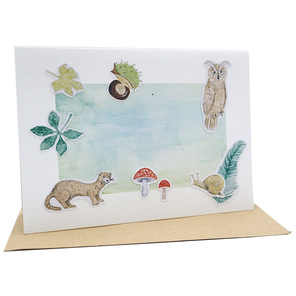 Klappkarte Waldbewohner mit Motiven wie Eule, Marder, Schnecke und Pilzen auf Aquarellhintergrund, darunter ein Kraftpapier Umschlag