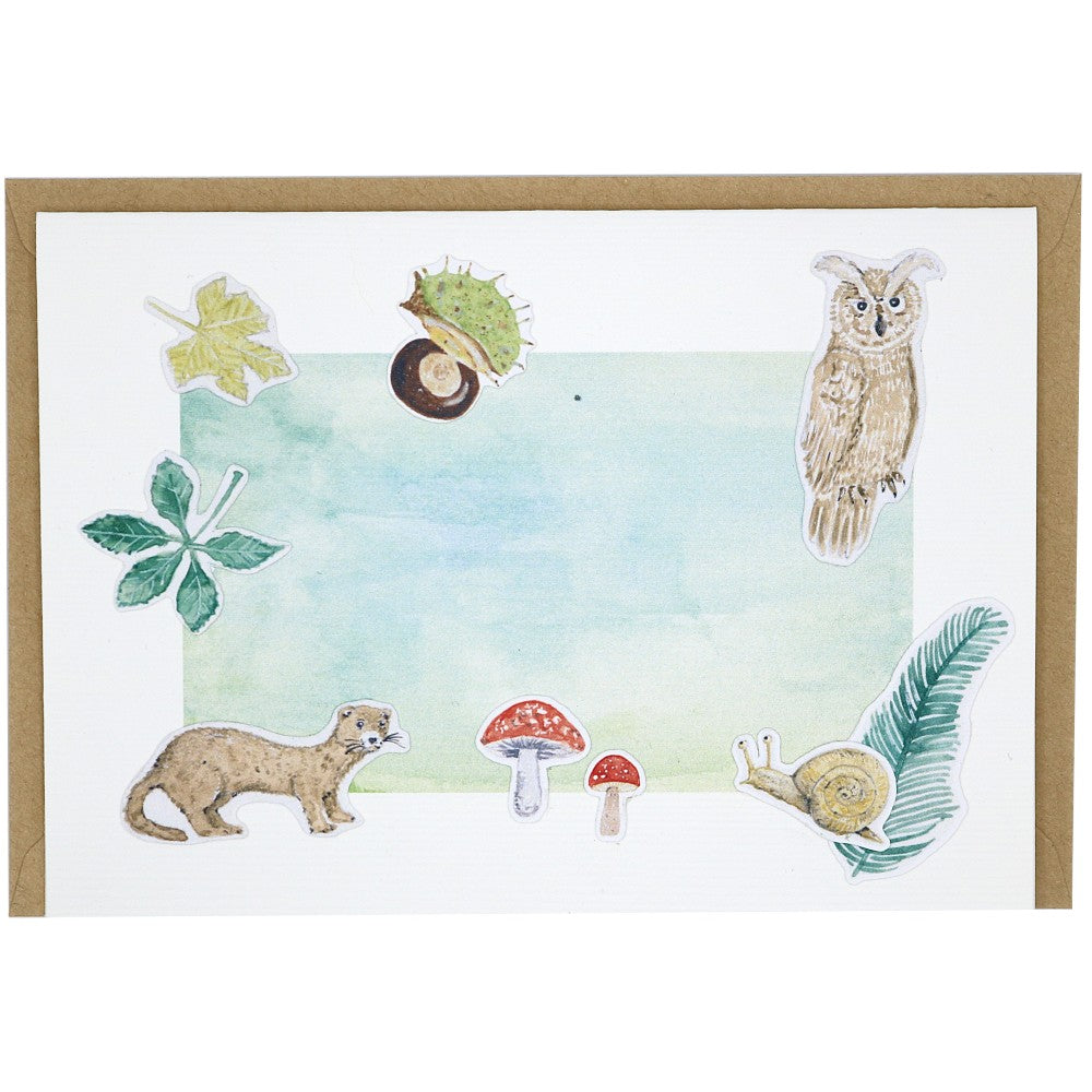 Grusskarte Waldbewohner mit Motiven wie Eule, Marder, Schnecke und Pilzen auf Aquarellhintergrund, dahinter ein Kraftpapier Umschlag