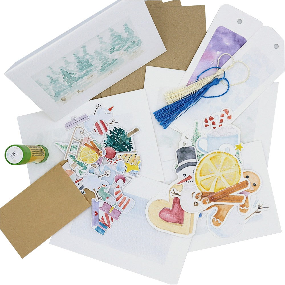 Xmas Special Kreativset mit mehreren Klappkarten auf strukturiertem Aquarellpapier, passenden Kraftpapierumschlägen, winterlichen Lesezeichen samt Quasten, weihnachtlichen Geschenk-Anhängern und Aquarellmotiven sowie einem Klebestift, alles dekorativ ausgelegt. perfekt zu Weihnachten. 